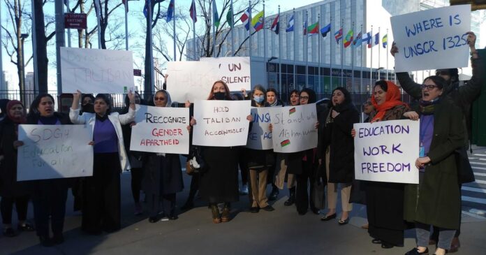 : A group of Afghan women holding banners and raising their voices in front of the UN headquarters, advocating for education rights.