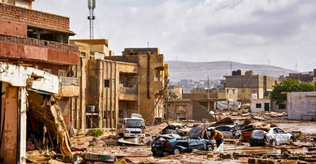 Damaged homes and overturned cars line the flooded streets of Derna